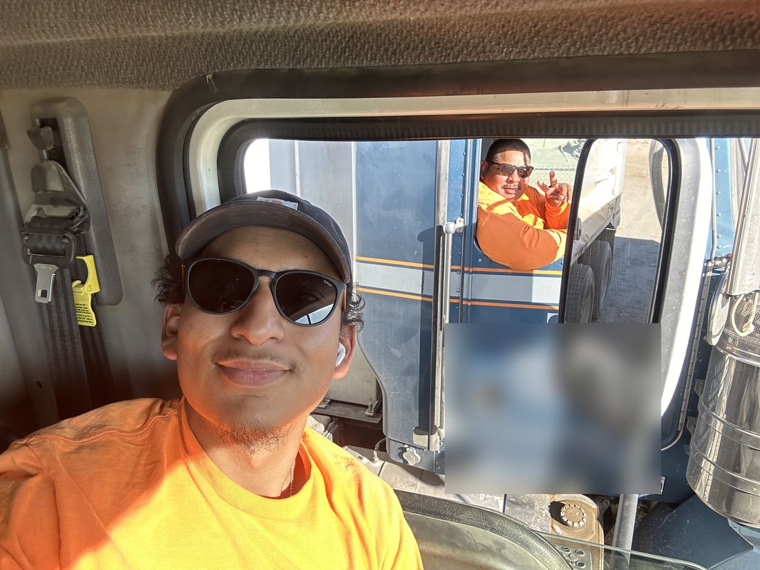Chel in his truck cab with his dad waving from the next truck