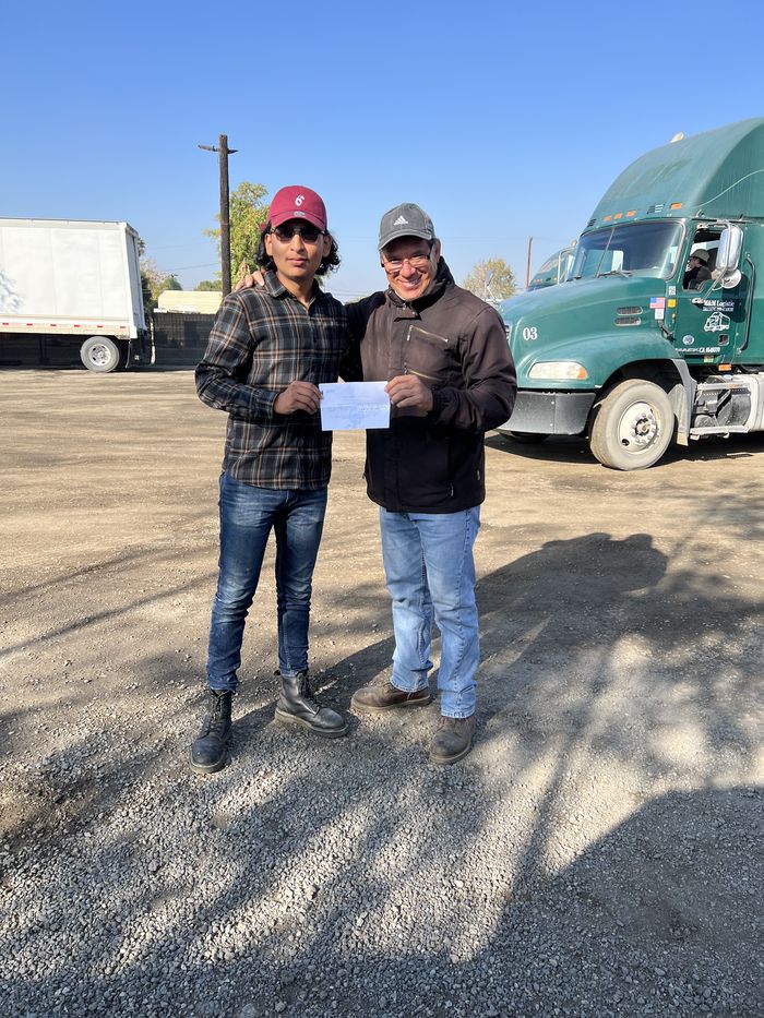 Chel holding his CDL school certificate next to a semi