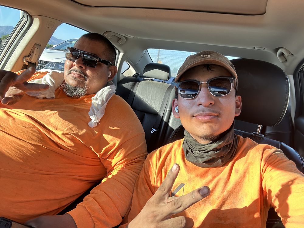 Chel and his dad in orange work shirts after a shift